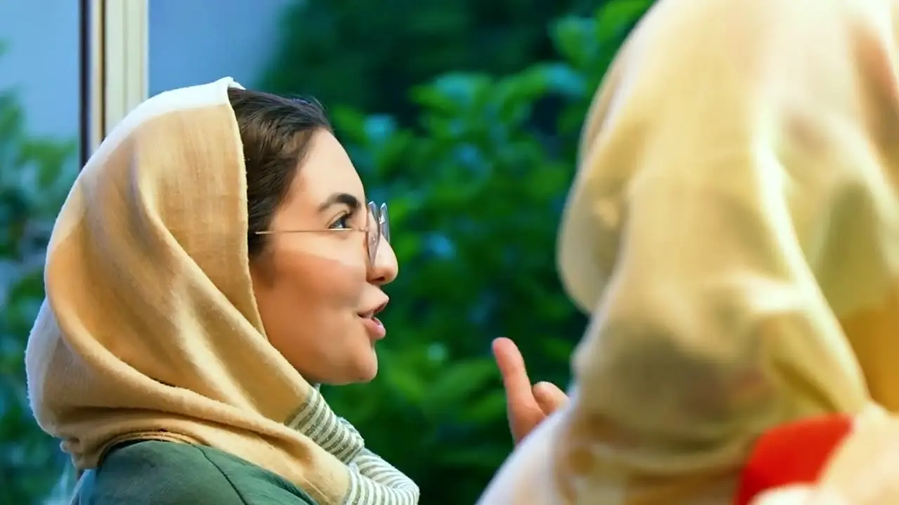 زنی با روسری زرد در حال گفت‌وگو و خنده در حیاط آموزشگاه